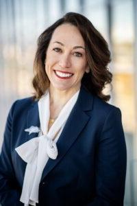 President Janine Davidson smiling, wearing a navy blazer with a white blouse